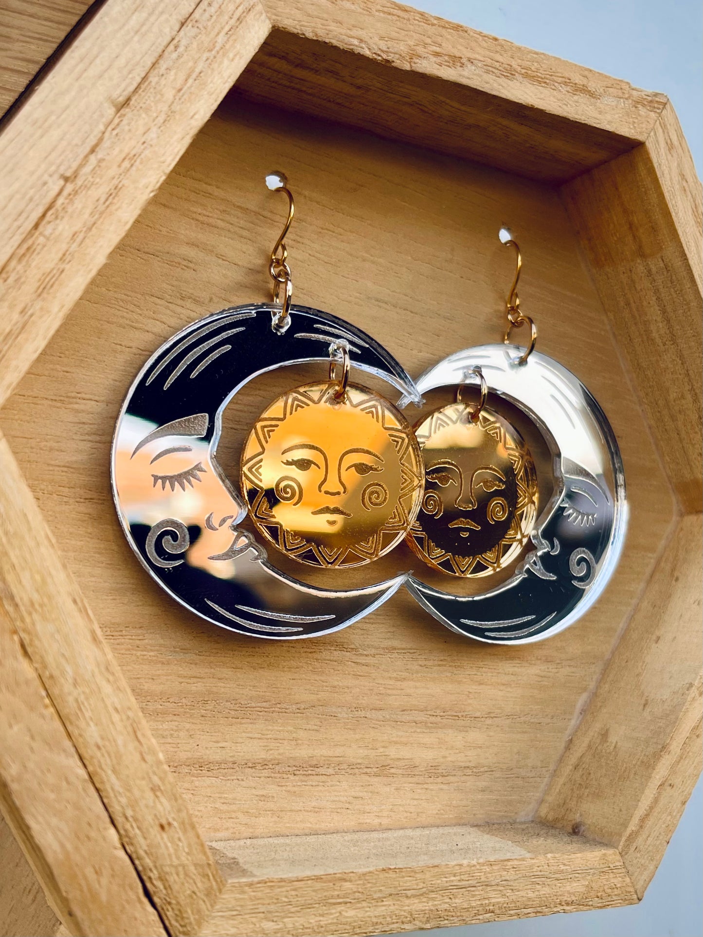 acrylic laser engraved crescent silver mirror moon with face with gold mirror sun with face earrings with gold colored hypoallergenic earring hooks.