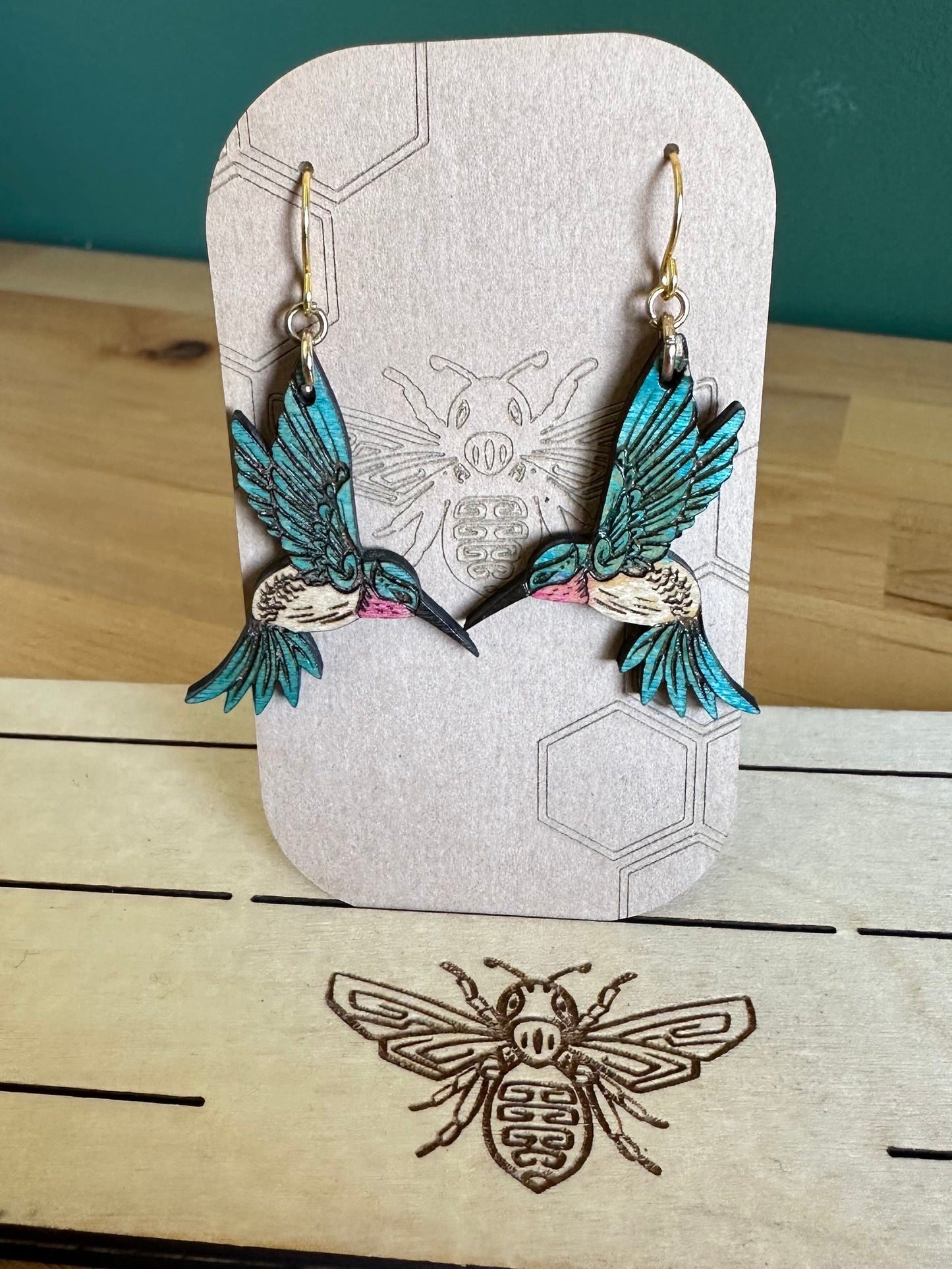 Blue and white Wood Hummingbird Earrings on gold colored hypoallergenic hooks on an earring card holder.