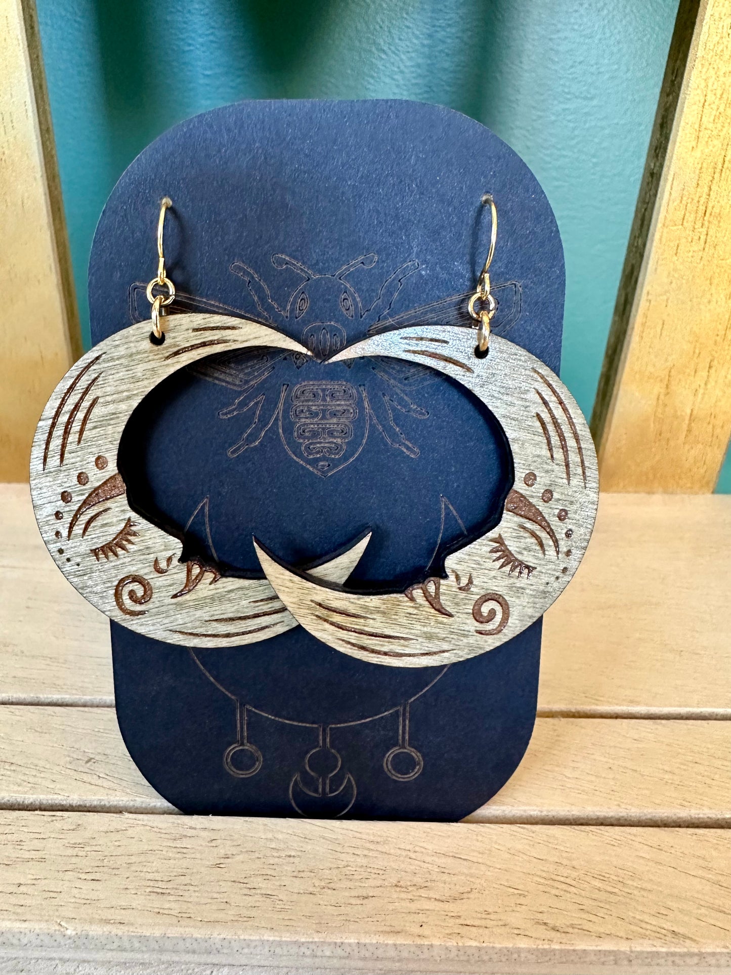 grey crescent moon wood earrings on gold colored hypoallergenic earring hook. Earrings on a black card stock earring holder.