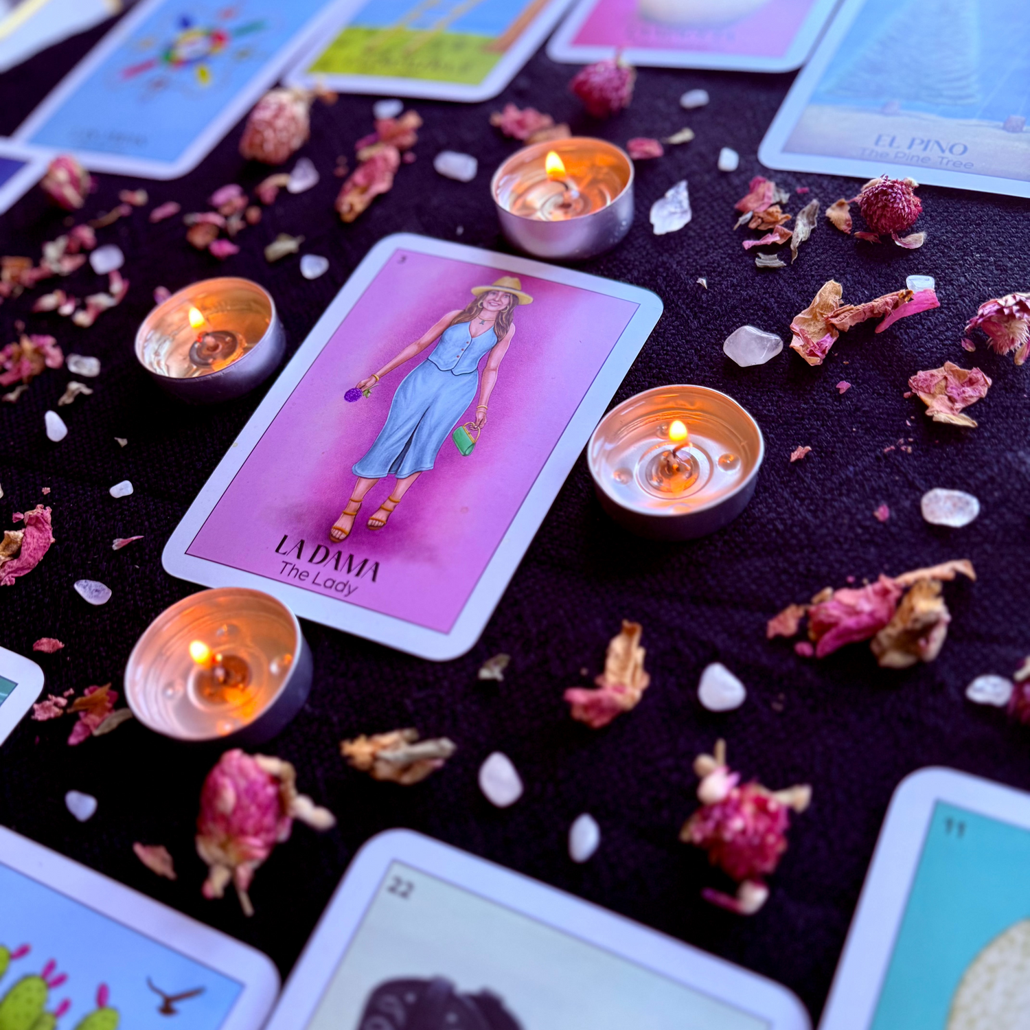 an oracle card reading with the center card being surrounded by tea light candles, crystals and rose petals.