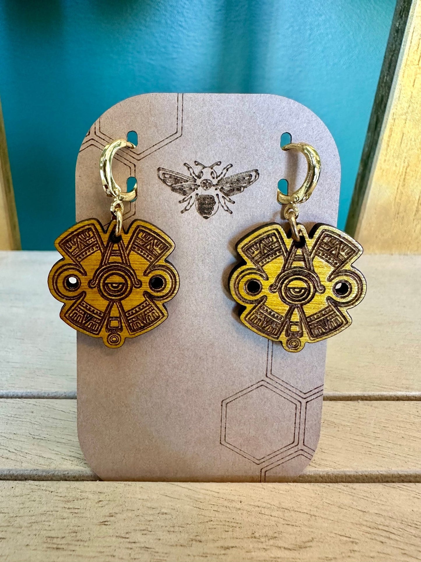 Ollin Earrings wood yellow toned on gold colored hypoallergenic hoops. Earrings on brown card stock earring holder.