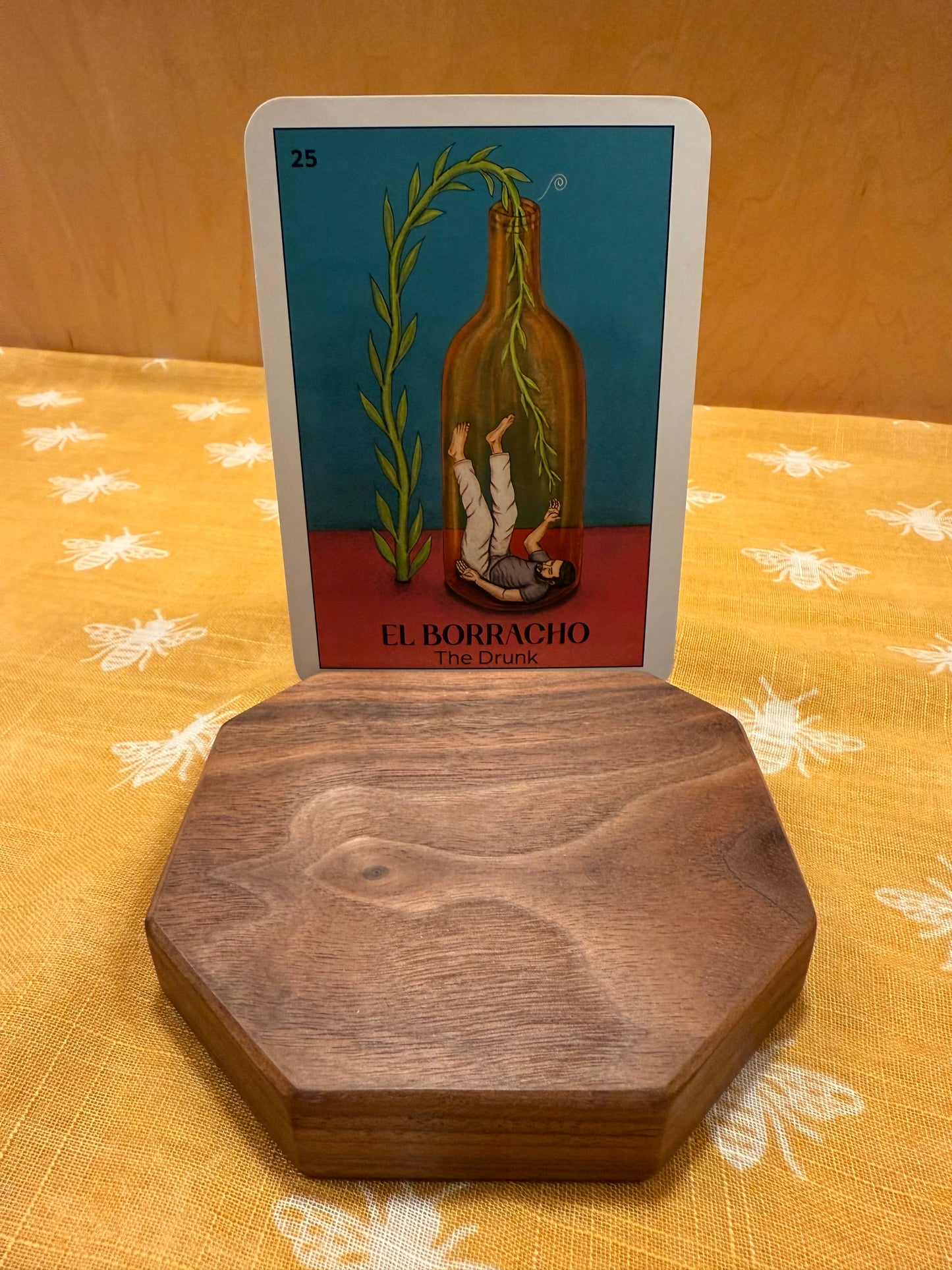 dark walnut tarot card holder with an oracle card on a patterned fabric. 