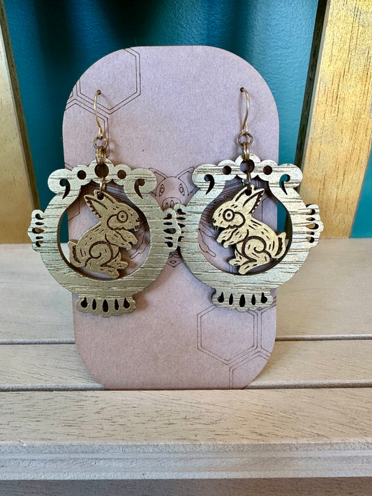 gold wood engraved tochtli rabbit moon earrings on gold colored hypoallergenic hooks. earrings on brown card stock earring holder. 