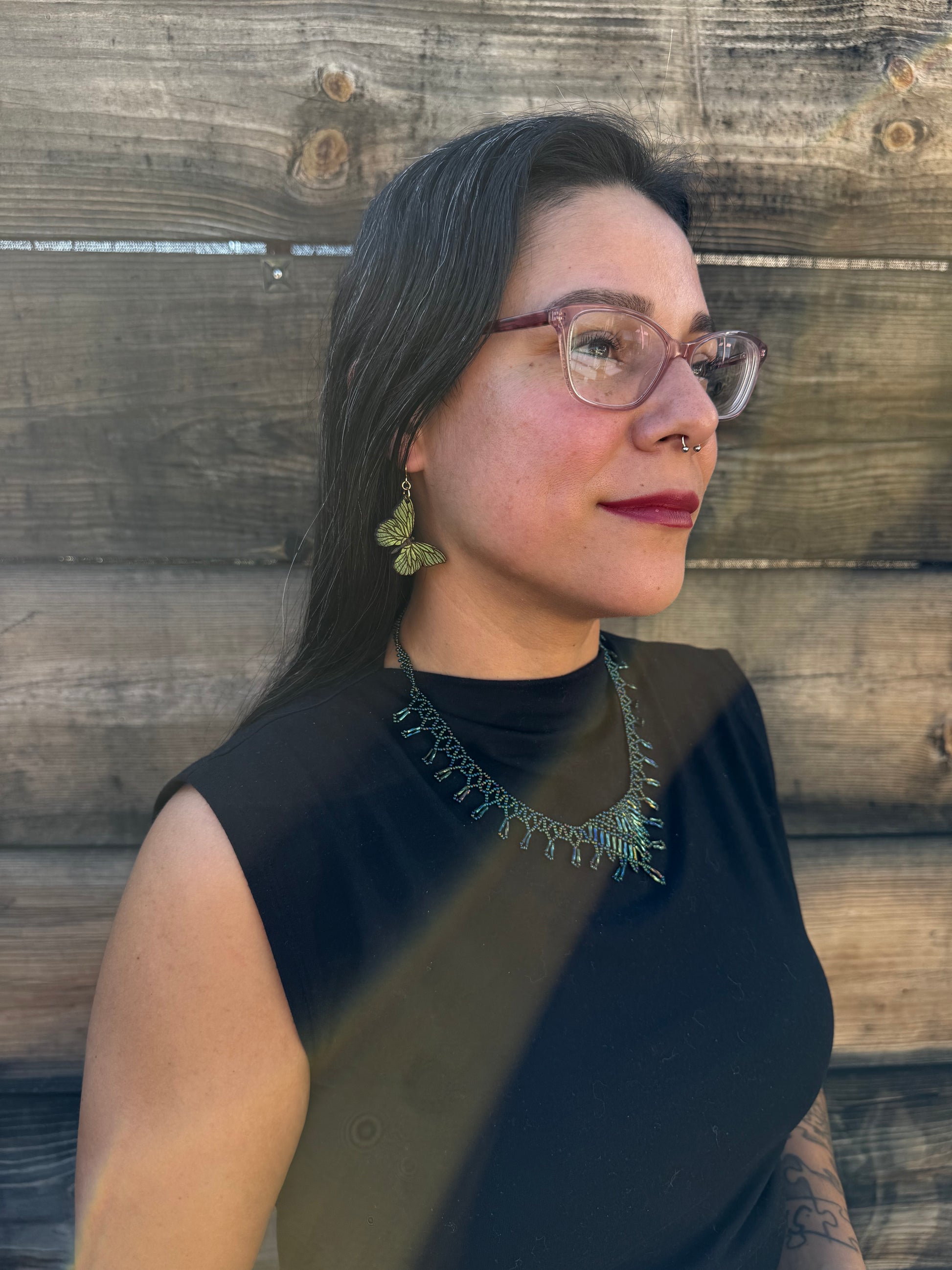 Person wearing green butterfly earrings.