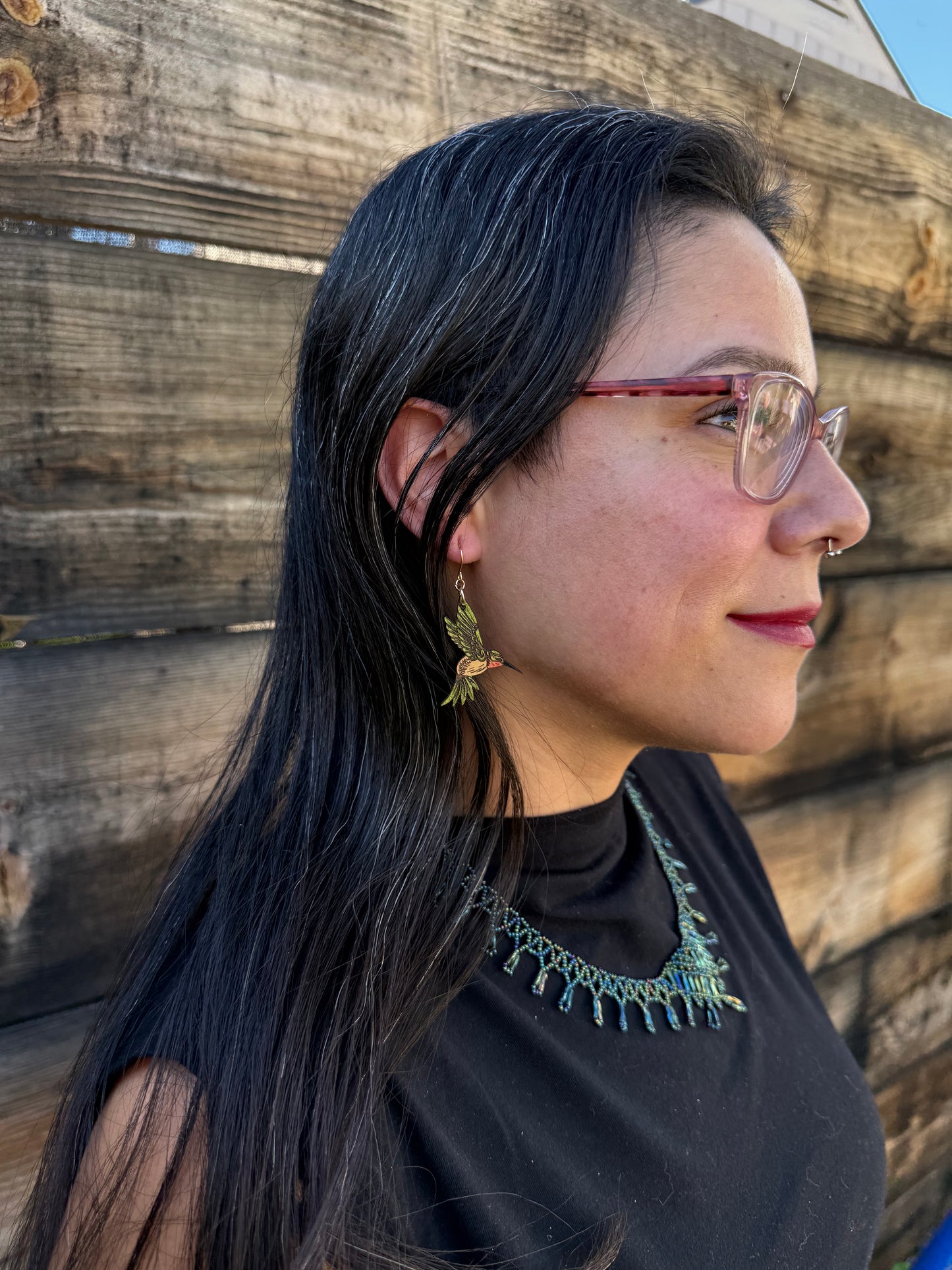 Woman wearing green hummingbird earrings. 