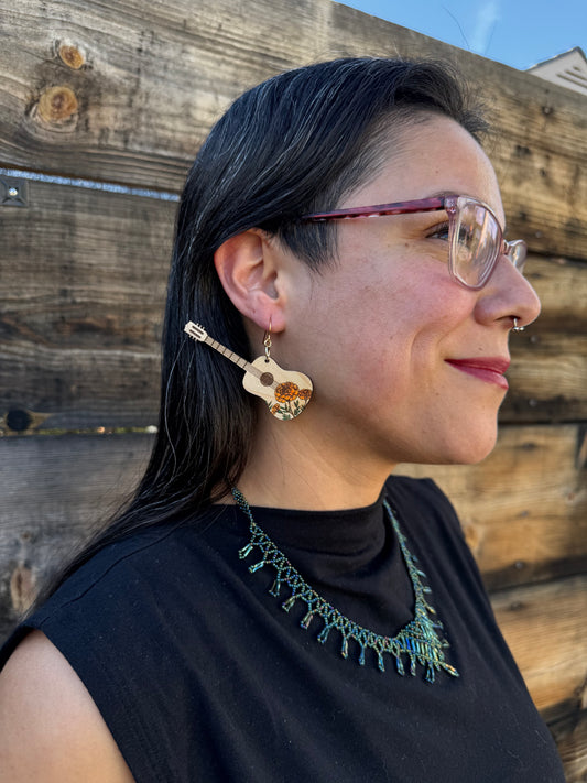 A side angle of a woman wearing marigold engraved wooden guitar earrings.