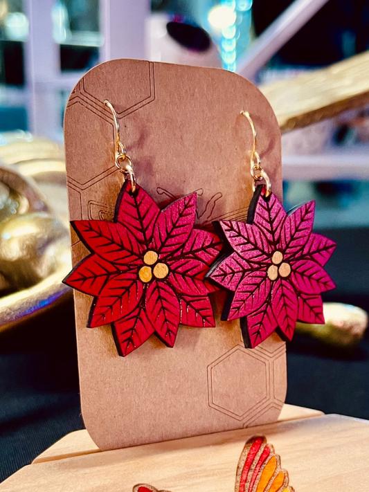 Wood engraved poinsetta noche buena red flower earrings on gold colored hypoallergenic nickel free hooks on a brown cardstock earring holder. 