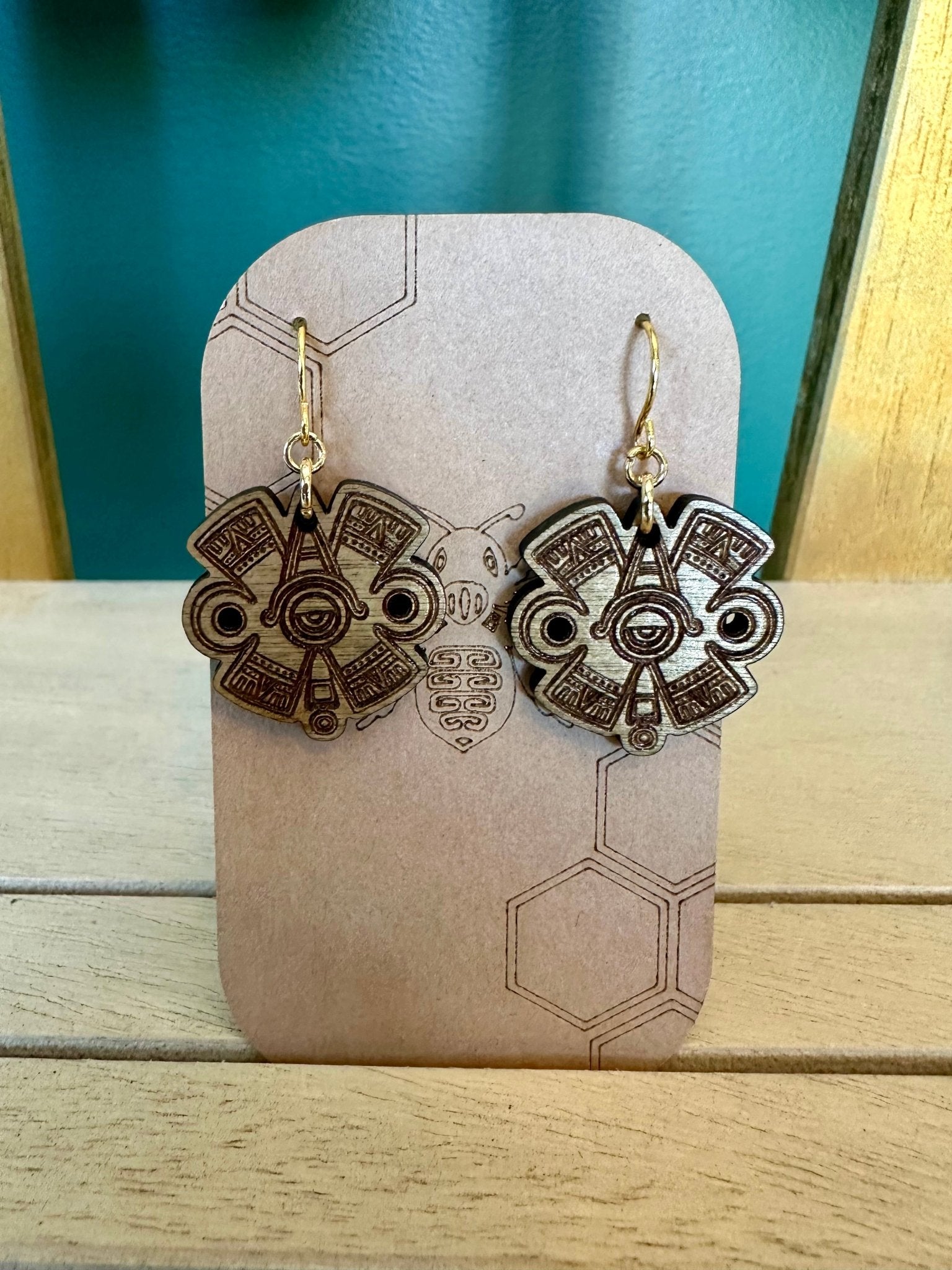 Ollin Earrings wood toned on gold colored hypoallergenic hooks. Earrings on brown card stock earring holder. 