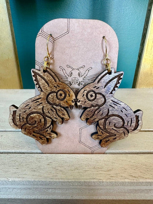 wood engraved brown toned  tochtli rabbit earrings on gold colored hypoallergenic hooks. earrings on brown card stock earring holder. 