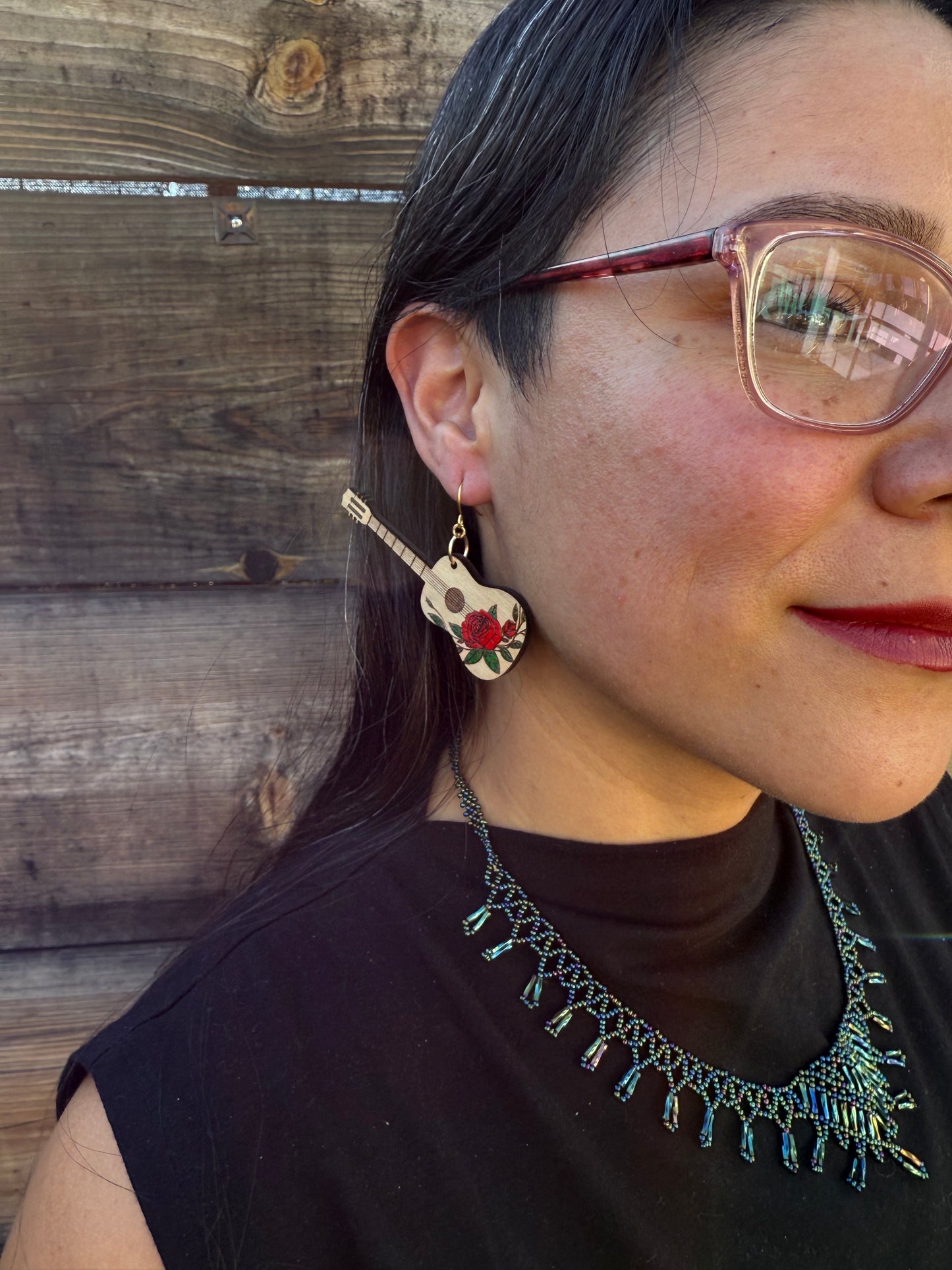 A side angle of a woman wearing red rose guitar earrings.