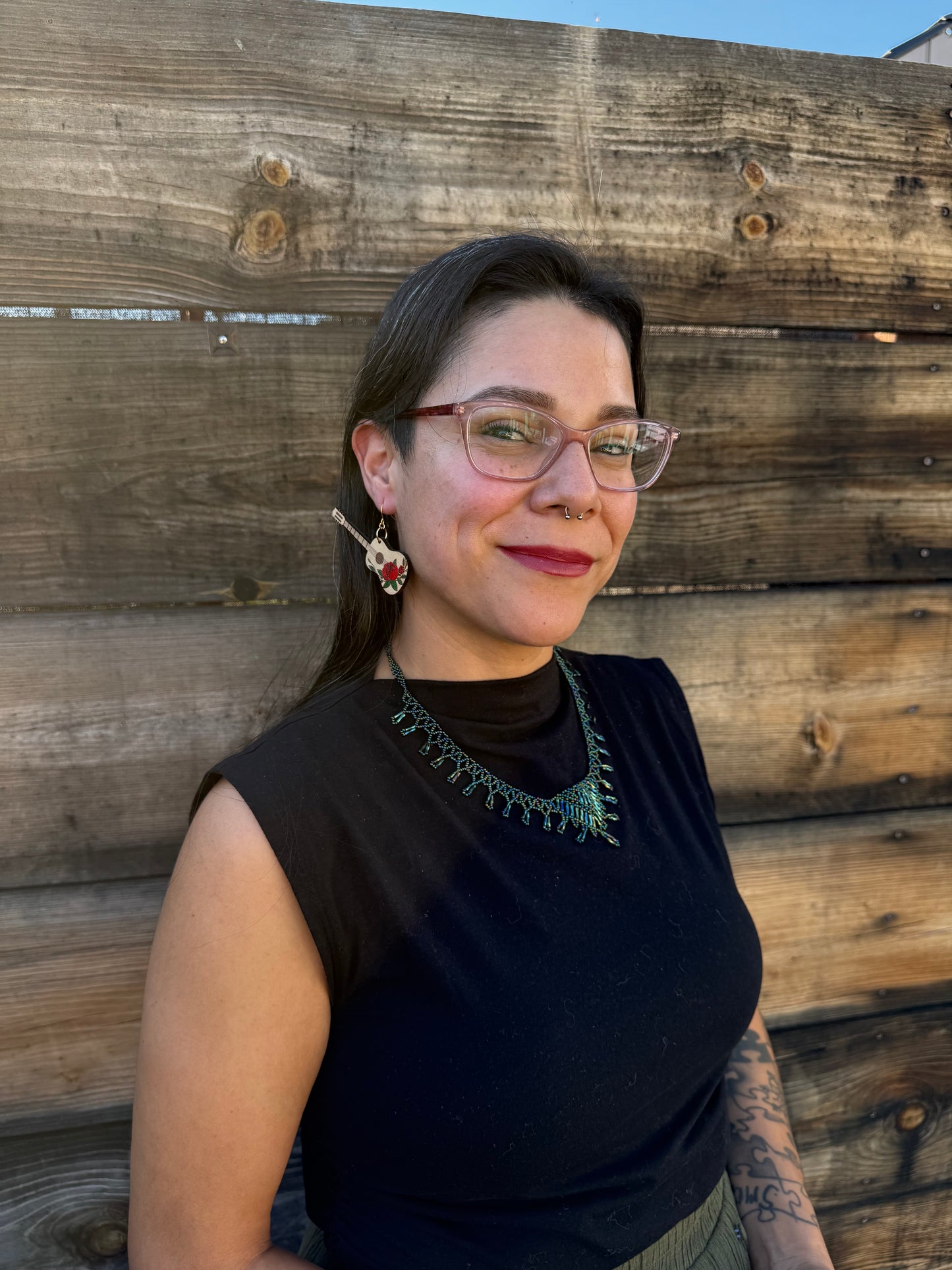 A woman wearing red rose guitar earrings.