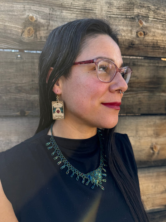 side angle of a woman wearing the lovers tarot with an engraving of hummingbirds and roses.