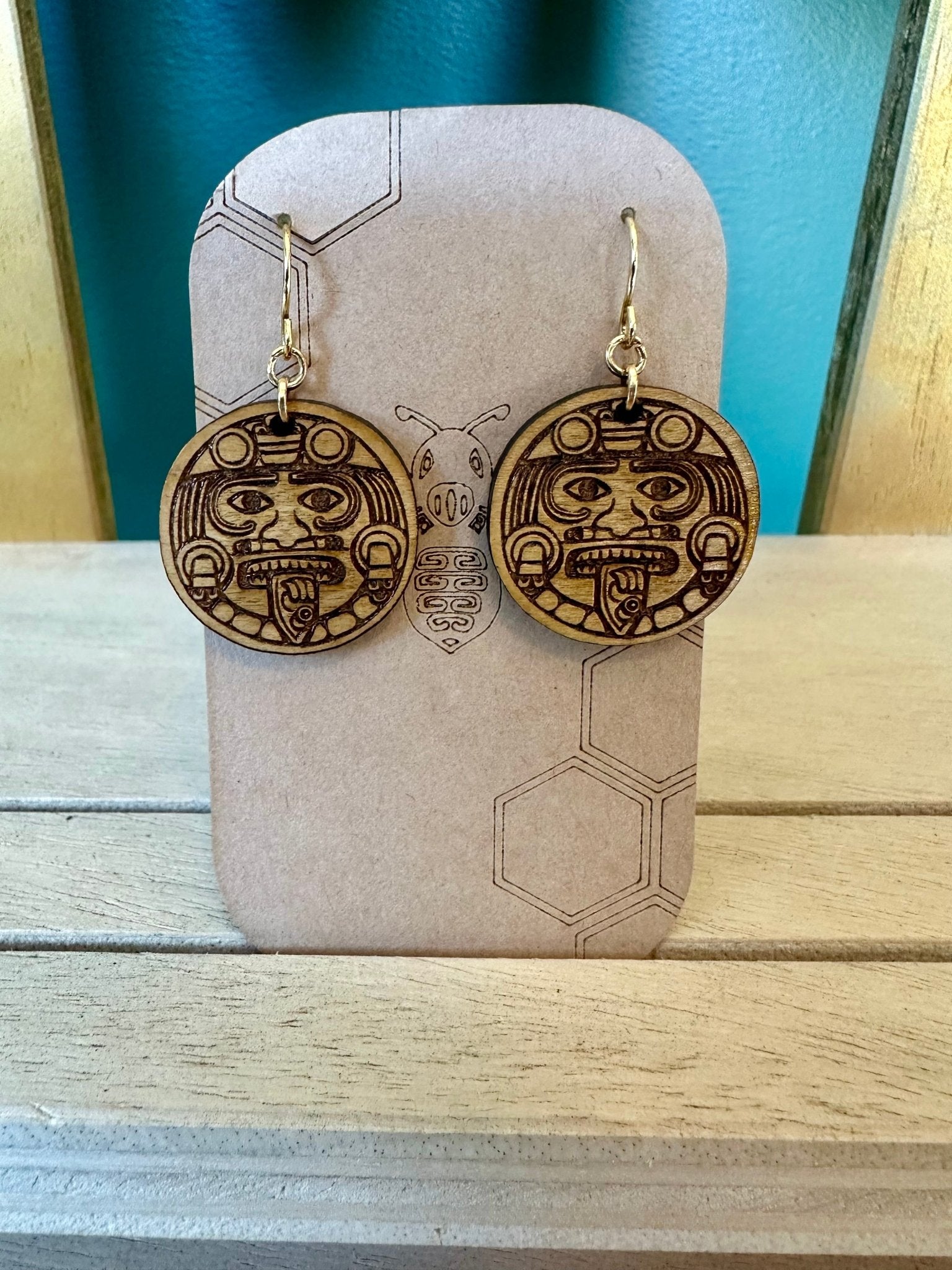 wood engraved Tonatiuh aztec sun  Earrings on a gold colored hypoallergenic earring hook. earrings on a brown card stock earring holder. 