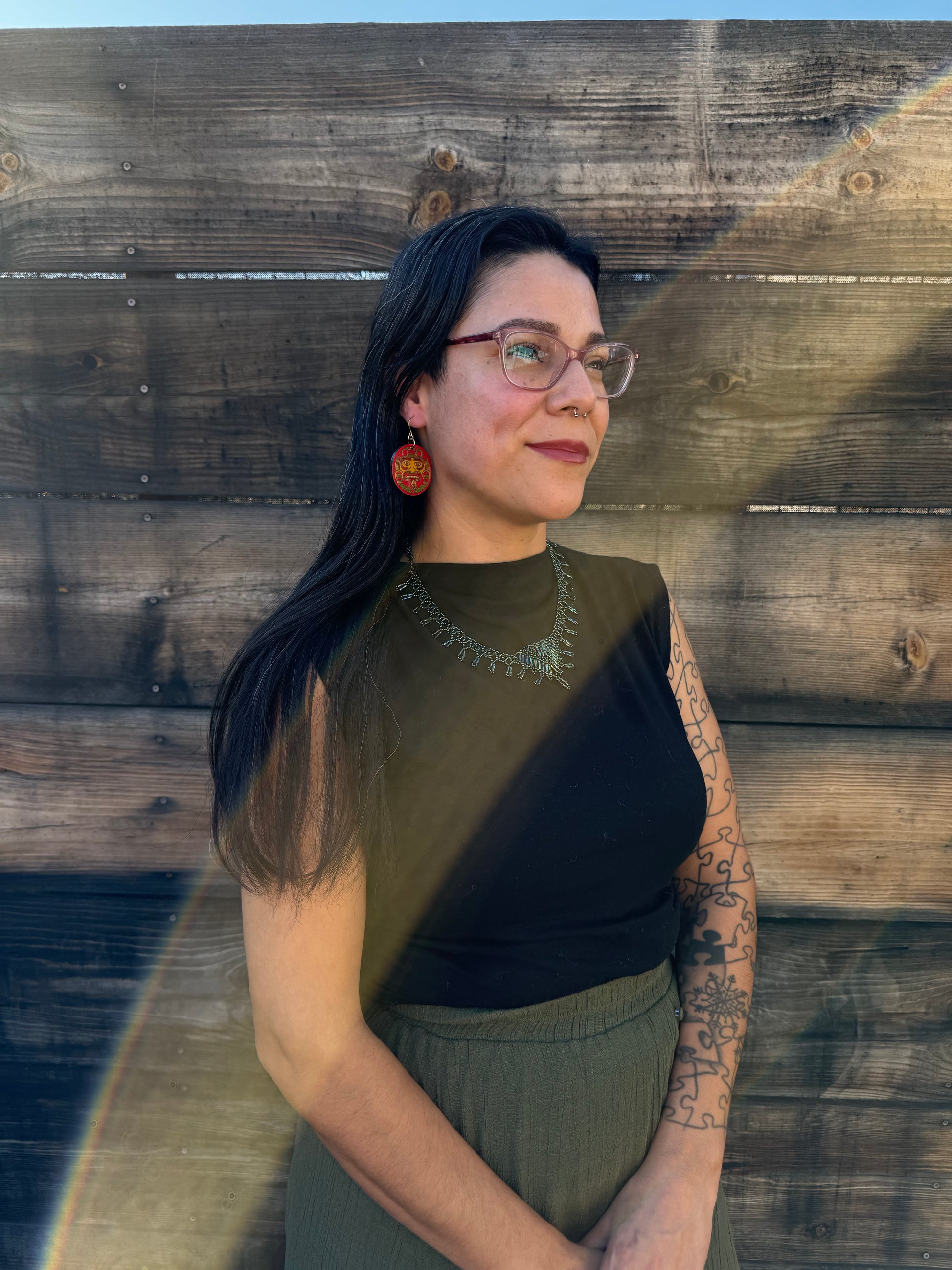 A woman wearing red and yellow tonatiuh sun earrings.
