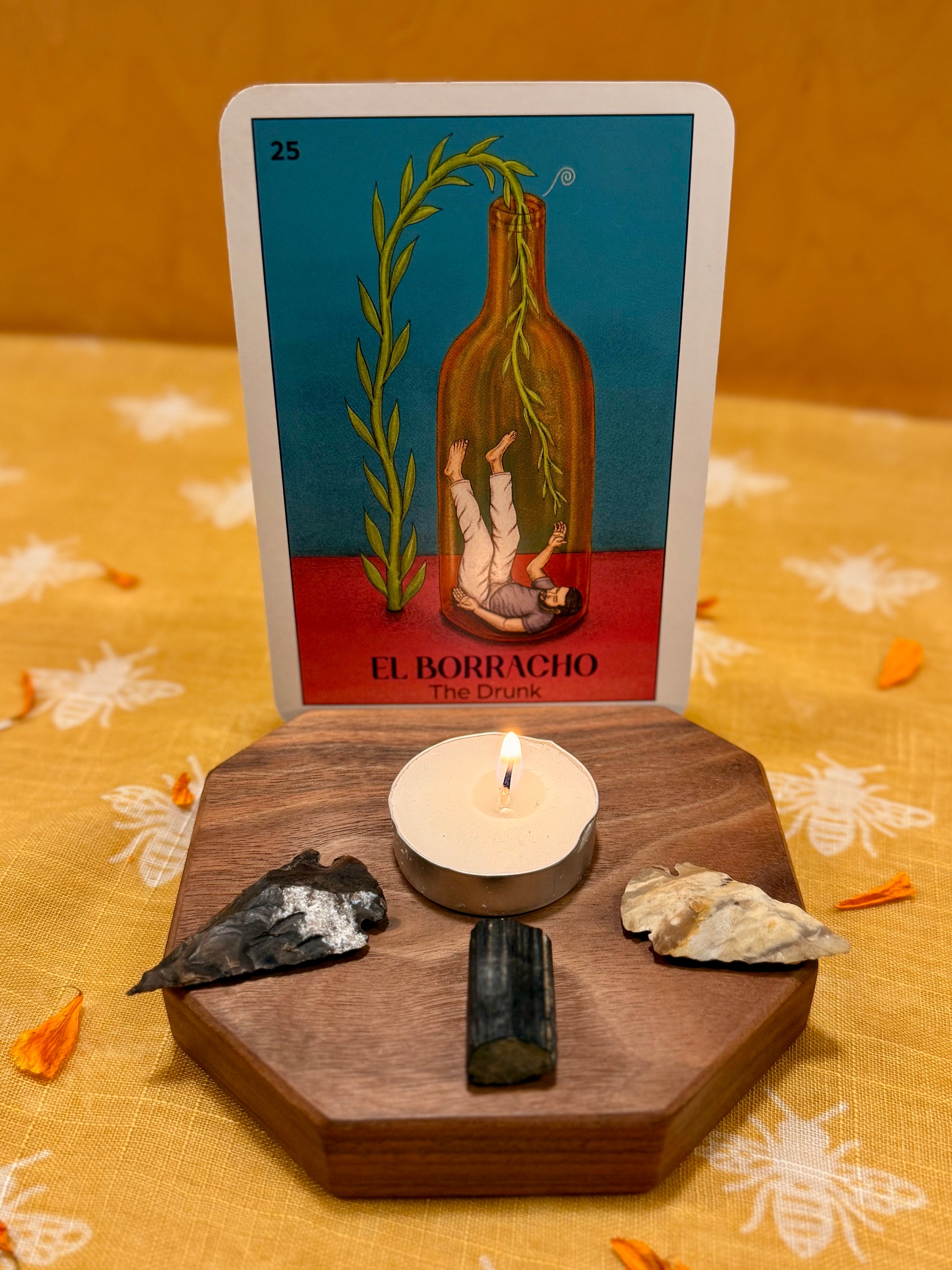 Tarot card featuring a bottle and candle with a lit candle and crystals on a wooden card holder.